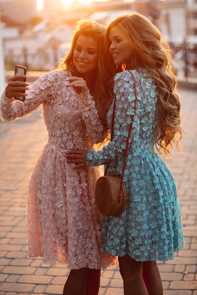 Hermosas damas haciendo fotos en el teléfono inteligente juntos . — Foto de Stock