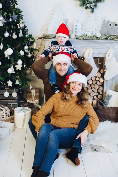 Familia feliz en los sombreros de Navidad en la chimenea . —  Fotos de Stock
