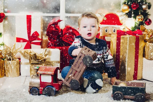 Menino loiro brincando com presentes e caixas de Natal . — Fotografia de Stock