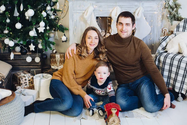 Familia sentados juntos en un sofá en un estudio decorado cerca del árbol de Navidad . —  Fotos de Stock