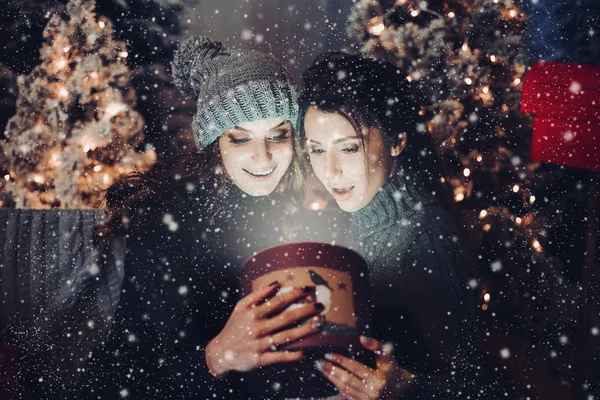 Två flickvänner öppna rutan med presentera på julnatten. — Stockfoto