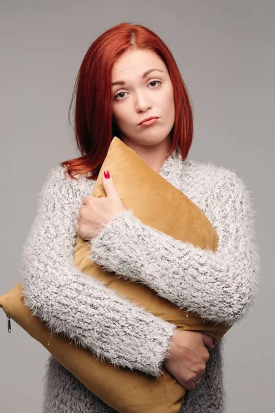 Retrato de estudio de una mujer en un suéter abrazando una almohada . —  Fotos de Stock