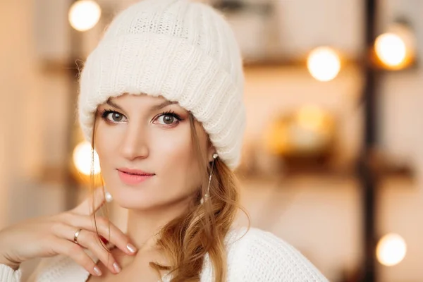 Preciosa mujer en sombrero de lana blanca y pendientes sobre fondo bokeh . — Foto de Stock