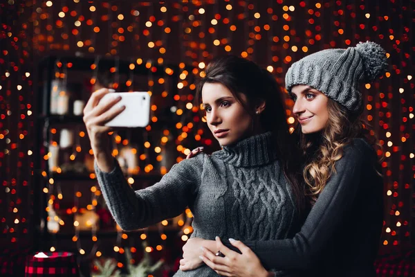 Systrarna omfamnar varandra och ta självporträtt på smart telefon. — Stockfoto