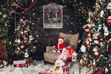 Küçük Noel baba çocuk Noel ağacı yakın büyük kol sandalyede oturan kırmızı paketindeki.