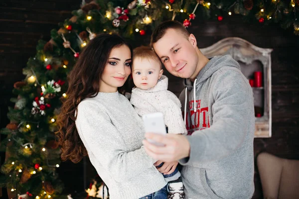 Família feliz com criança adorável se divertindo na árvore de Natal . — Fotografia de Stock