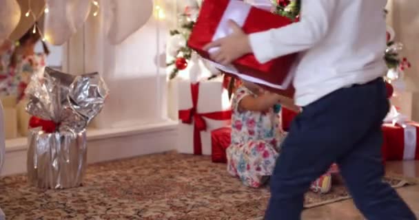Діти з різдвяними подарунками під ялинкою . — стокове відео
