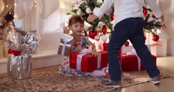 Kinderen met Kerstmis cadeautjes onder de kerstboom. — Stockvideo