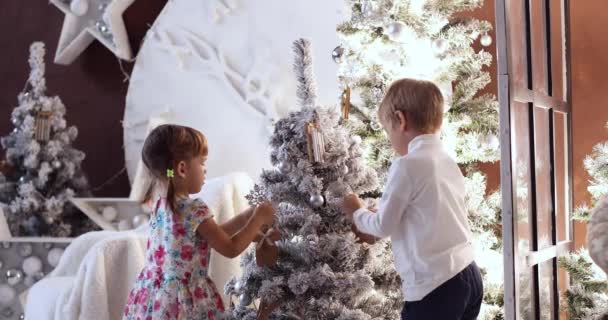 Decoraciones navideñas, tiempo en familia, niño al lado del árbol de Navidad. Un chico jugando en casa. Concepto de vacaciones de invierno de Navidad. Feliz Año Nuevo y felices fiestas . — Vídeo de stock