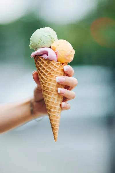Tender womans hand keeping delicious colorful ice cream.