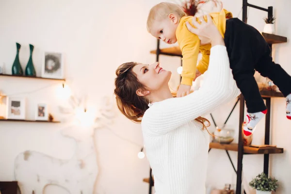 Madre encantadora levantando a su bebé y sonriéndose el uno al otro . —  Fotos de Stock