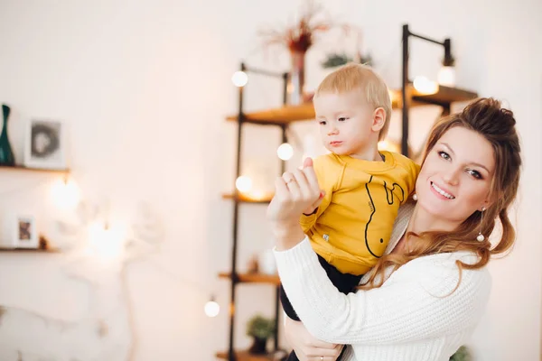 Madre encantadora levantando a su bebé y sonriéndose el uno al otro . —  Fotos de Stock