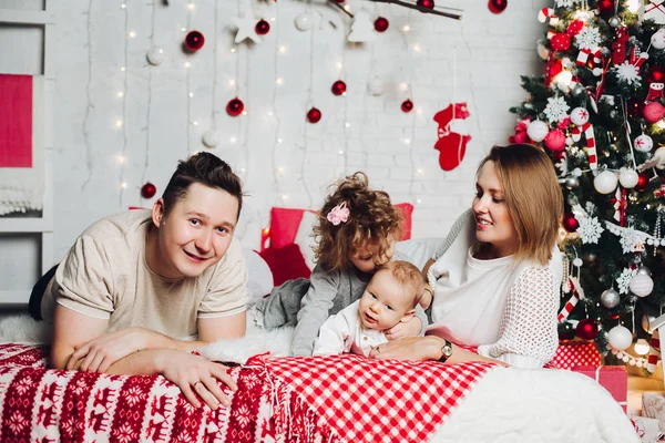 Prachtige familie in ingerichte slaapkamer bij ingerichte fir tree liefdevolle. — Stockfoto