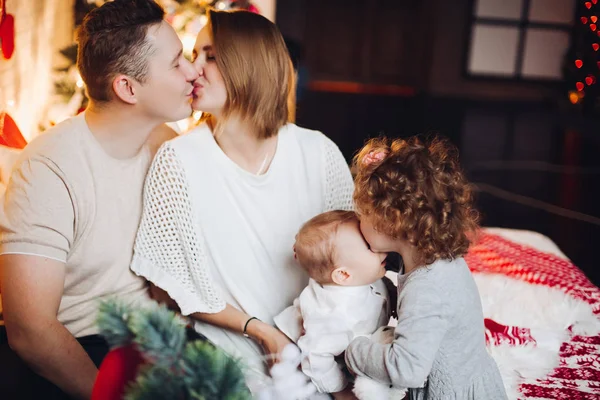 Kissing parents with hugging kids at Christmas. — Stock Photo, Image