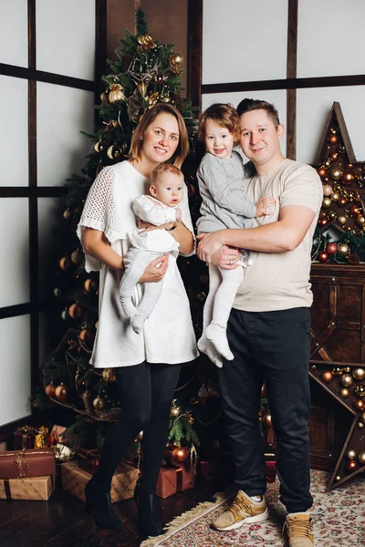 Gelukkig gezin met twee kinderen bij de kerstboom. — Stockfoto