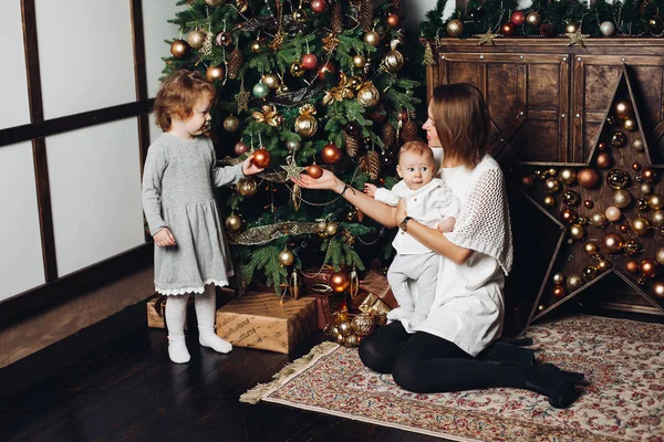 Madre con dos hijos en el árbol de Navidad . — Foto de Stock