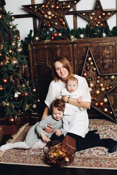 Madre con dos hijos en el árbol de Navidad . —  Fotos de Stock