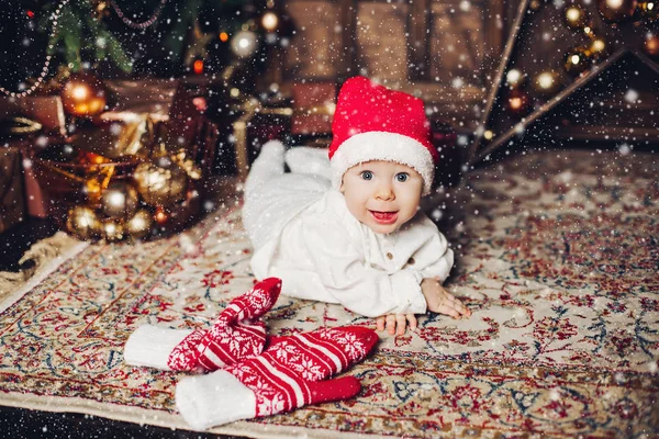 Bayi manis yang bahagia dengan topi merah di karpet dengan sarung tangan musim dingin yang lucu . — Stok Foto