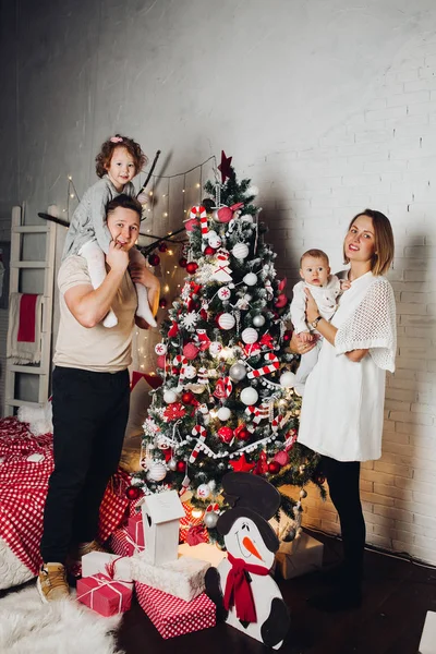 Gelukkig gezin met twee kinderen bij de kerstboom. — Stockfoto