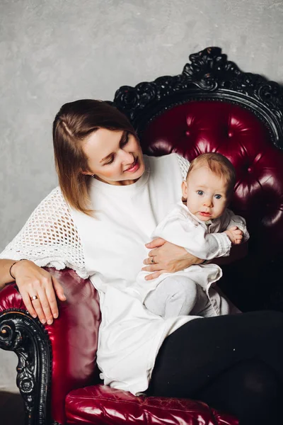 Vackra glad mamma med bebis i fåtölj. — Stockfoto