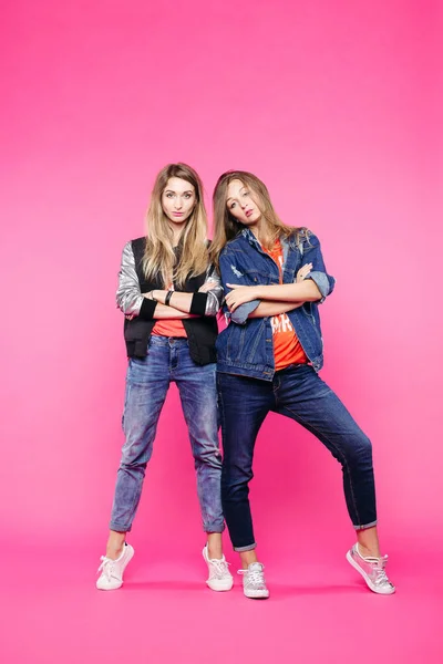 Hermanas hipster de moda en jeans posando con brazos cruzados . — Foto de Stock