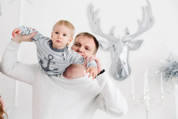 Padre encantador manteniendo hijo en las manos, abrazándolo y besándolo en el estudio de Navidad —  Fotos de Stock