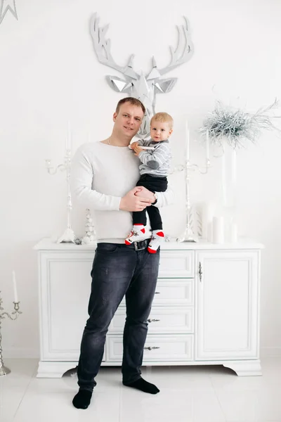 Padre encantador manteniendo hijo en las manos, abrazándolo y besándolo en el estudio de Navidad —  Fotos de Stock