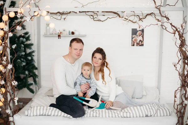 Mor och far med söt son ligga på sängen och tittar på kameran i studion i vintern — Stockfoto
