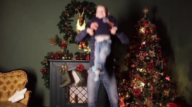 Baba ve oğul şenlikli Santa s şapkalar oynama ve büküm olarak dekore edilmiş Noel ağacı yakınındaki. Baba çevresinde ellerinde oğluyla büküm. Oğlu öpüşme. Yeni yıl kavramı.