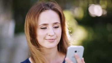 Gülümseyen güzel kadın cep telefonu açık havada yolu ile konuşmak.