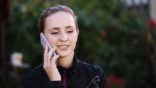Chica bonita con cola hablando en el teléfono inteligente y mostrando emoción . — Vídeos de Stock
