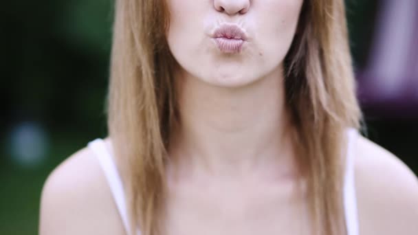 Жінка дме поцілунок на камеру на відкритому повітрі . — стокове відео