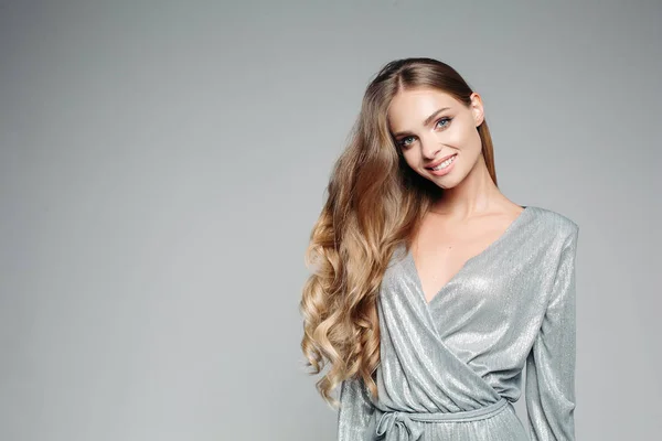 Mujer rubia de pelo largo en traje de plata brillante sonriendo a la cámara . — Foto de Stock