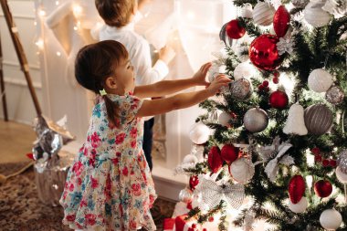 Bebek güzel kız şirin elbise ile lots-in Noel bankta oturmuş kafa bandı ile gülümseyen sunar.