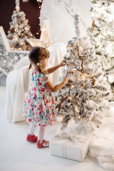 Усміхнена мила дівчинка в милій сукні з великою кількістю різдвяних подарунків . — стокове фото