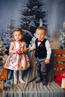 Dekorasyon ve Noel ağacının yakınında yeşil Noel yay ile oynayan iki küçük çocuklar.