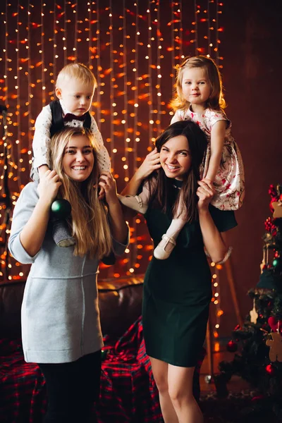 Két anya ül a aranyos gyerekek karácsony bemutat. — Stock Fotó