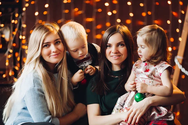 Two mothers sitting with cute kids christmas presents. — Stock Photo, Image