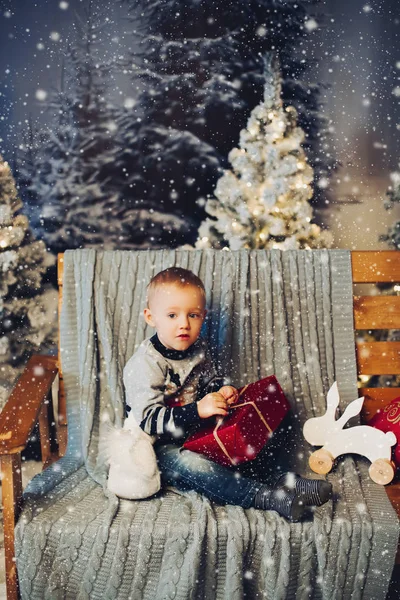 Sorrindo lindo bebê d sentado no banco com muitos presentes de Natal. — Fotografia de Stock