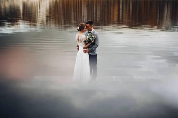 Whire と湖の中でのグレーの立っている新郎のカップルの花嫁. — ストック写真