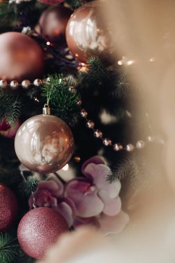 Pembe kareli yay ve şeritler ve yangın yeri yakınındaki şenlikli ruh hali ile Noel ağacı.