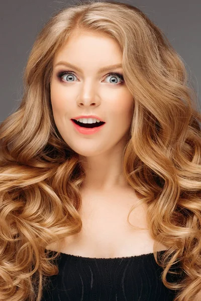 Lachendes blondes Mädchen mit langem und glänzendem welligem Haar. schöne lächelnde Frau Modell mit lockiger Frisur . — Stockfoto