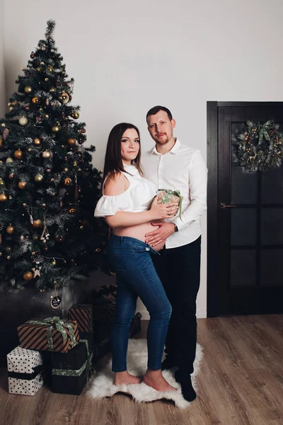 Homem e mulher grávida posando perto da árvore de Natal . — Fotografia de Stock