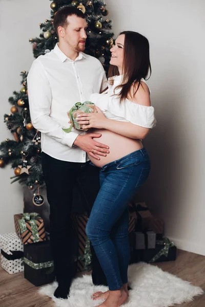 Homem e mulher grávida posando perto da árvore de Natal . — Fotografia de Stock