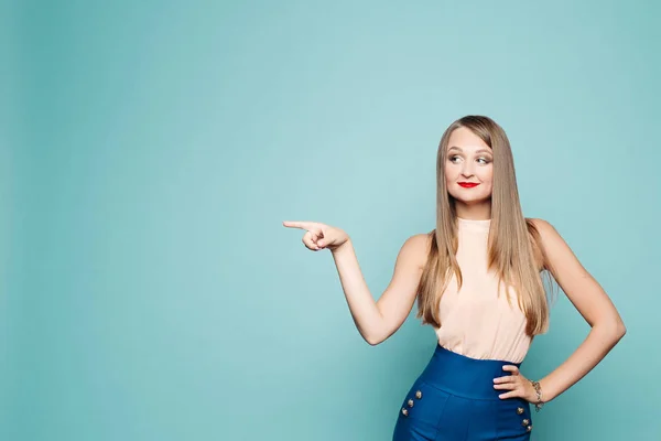 Porträt einer blonden Frau in eleganter Kleidung, die etwas mit dem Finger demonstriert. — Stockfoto