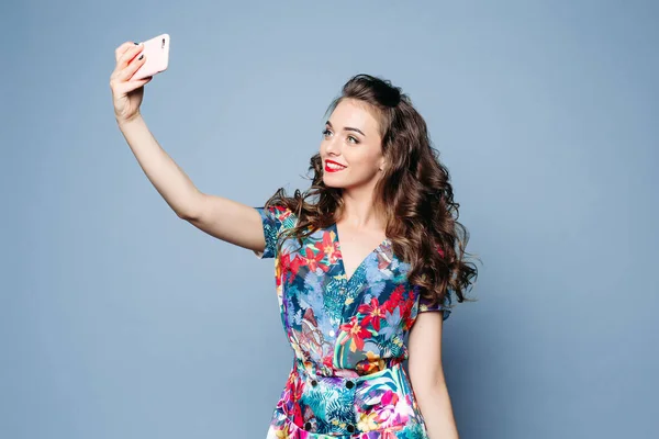 Lovely girl in floral dress taking selfie with mobile phone over — Stock Photo, Image