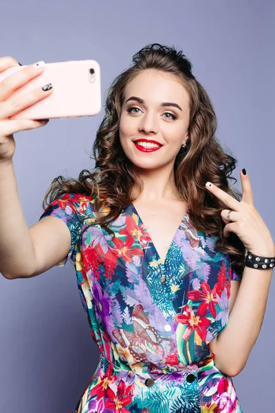 Fashionable woman showing peace and taking photo of herself.
