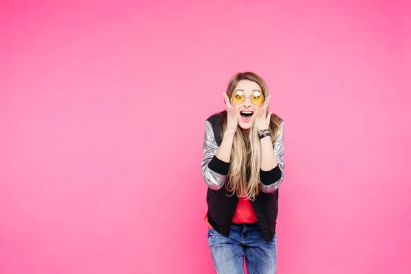 Emotion tonåring flicka i gul sunglaases mot rosa studio bakgrund. — Stockfoto