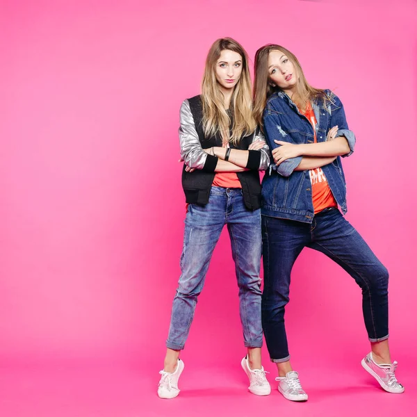 Dos hipster con estilo de pie con las manos cruzadas y posando en el estudio rosa . — Foto de Stock