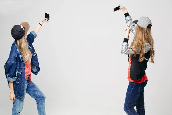 Dos chicas con ropa elegante tomando selfie en el teléfono inteligente . —  Fotos de Stock